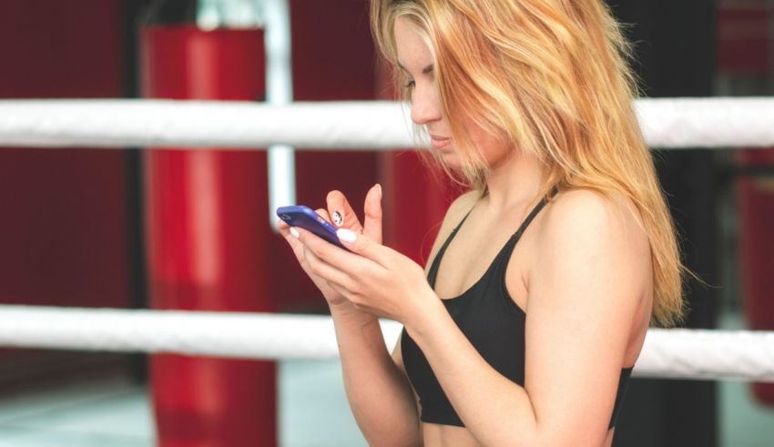 A woman is using her cell phone in a boxing ring.