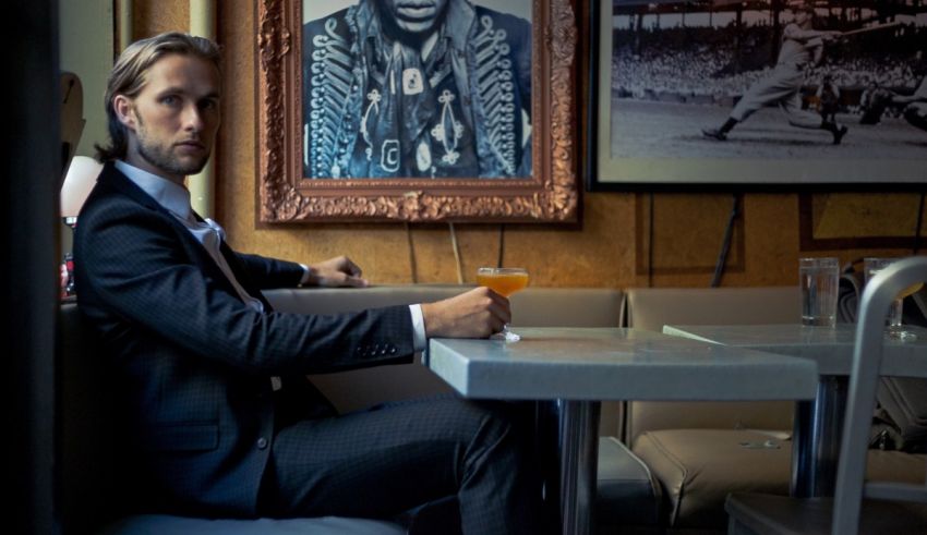 A man in a suit sitting at a table with a drink.