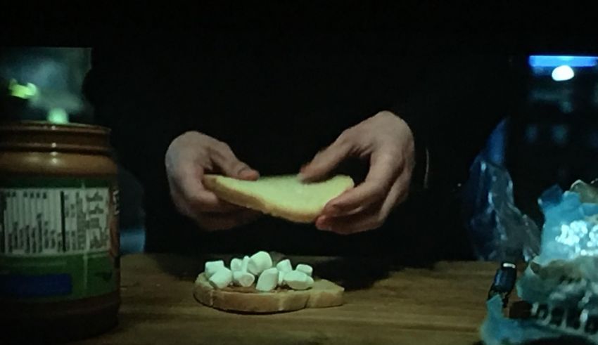 A person holding a piece of bread with marshmallows.