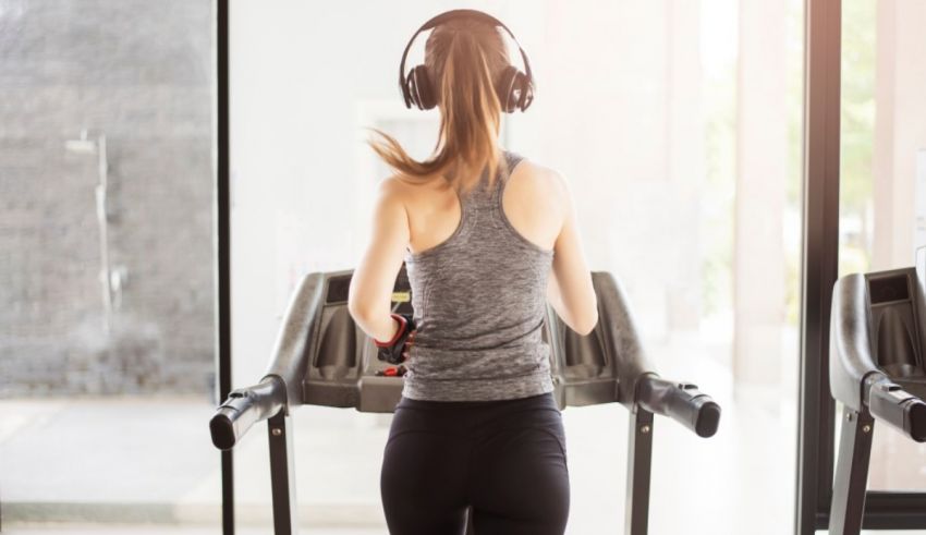 A woman is running on a treadmill with headphones on.
