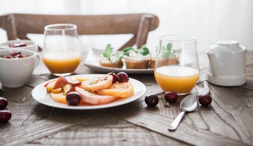 Breakfast with orange juice and fruit on a wooden table.
