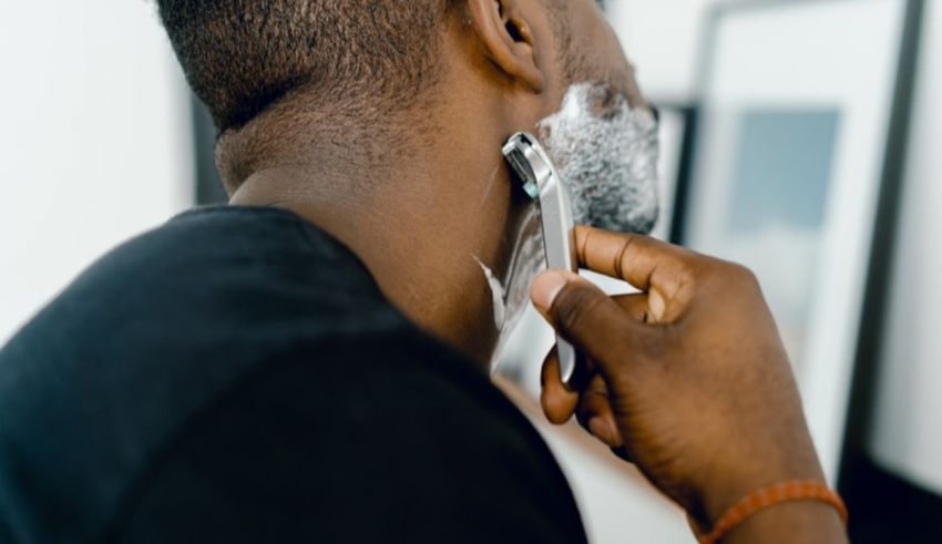 A man shaving his beard in front of a mirror.