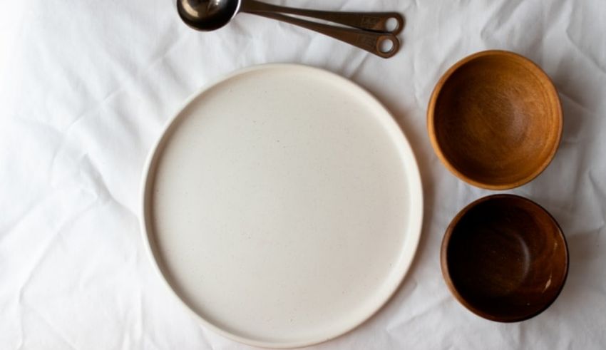 A white plate and two bowls on a white surface.