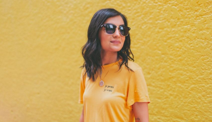 A woman wearing sunglasses and a yellow shirt.