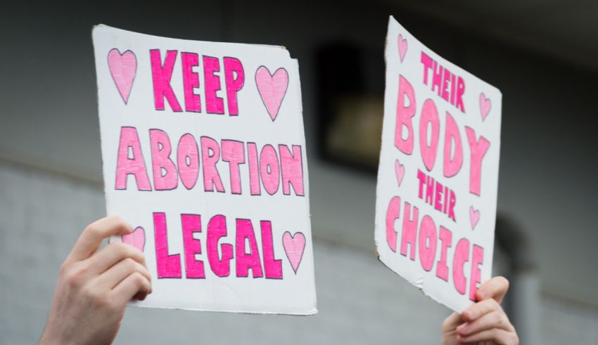 Two people holding up signs that say keep body abortion legal.