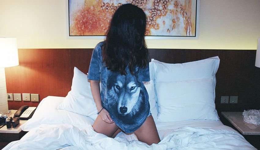 A woman is sitting on a bed in a hotel room.