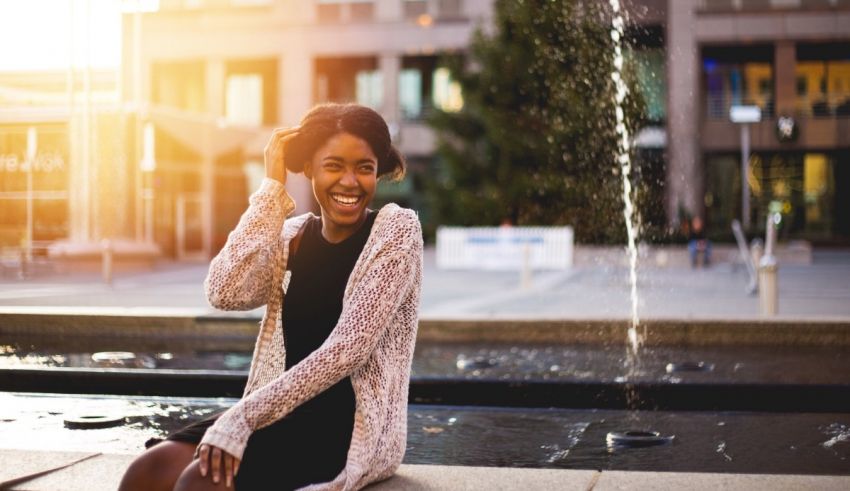 A woman sitting on a bench in front of a fountain.