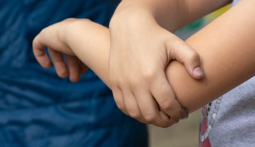 A child is holding his arm with his hand.