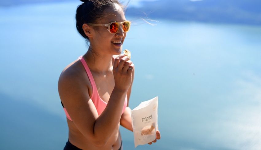 A woman is eating a piece of food while standing on top of a mountain.