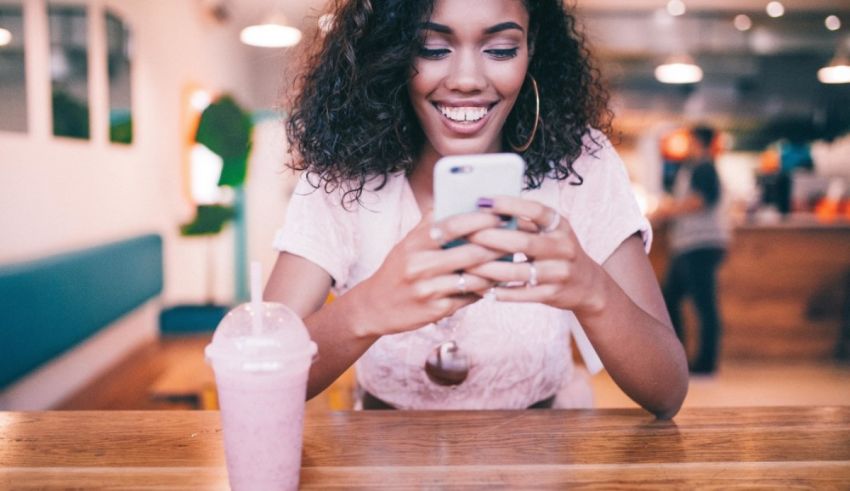 A woman smiling while looking at her phone.