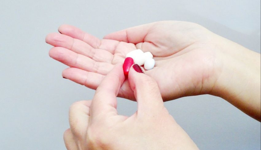A person holding a white pill in their hand.