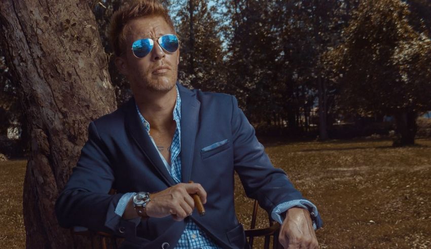 A man in a suit and sunglasses sitting in a chair.