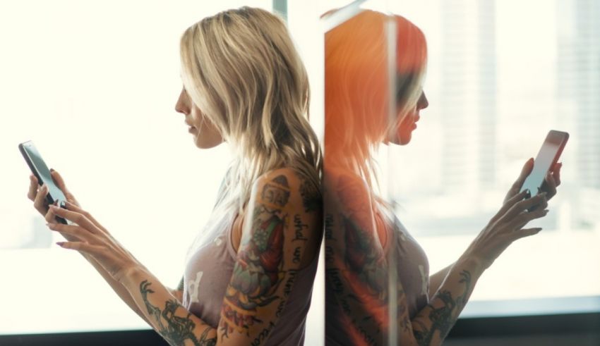 A woman with tattoos is using a cell phone.