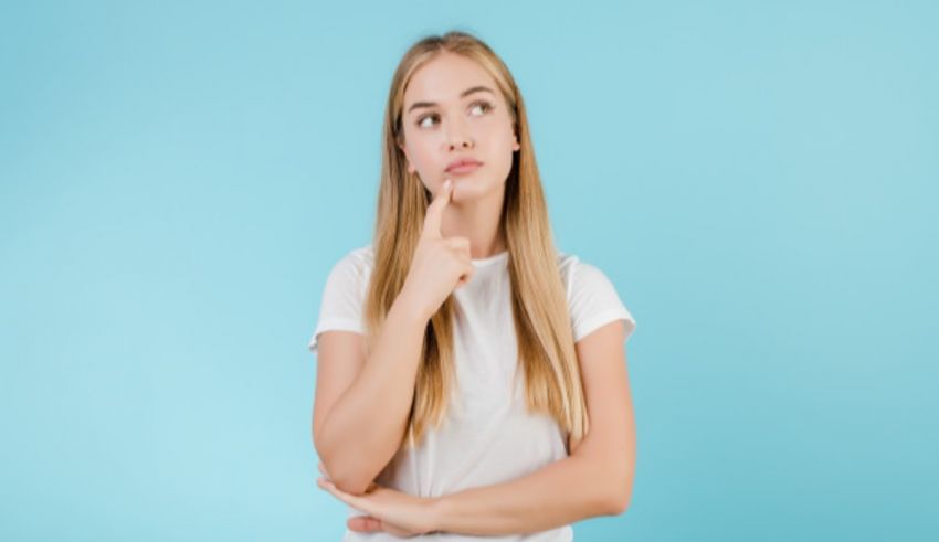 A young woman with her finger on her chin thinking about something.