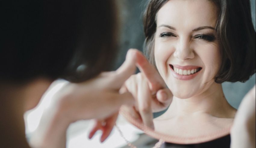 A woman smiling and holding a necklace.