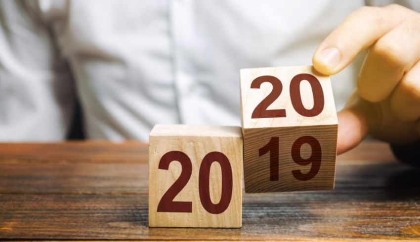 A man is holding a wooden block with the numbers 2019 and 2020 on it.