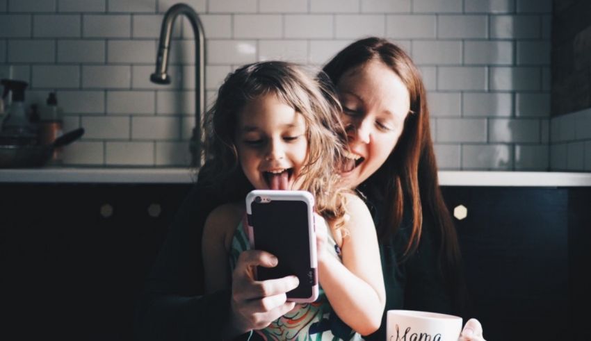 A mother and daughter laughing while holding a cell phone.