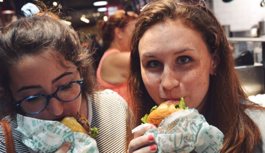 Two women eating burgers in a restaurant.