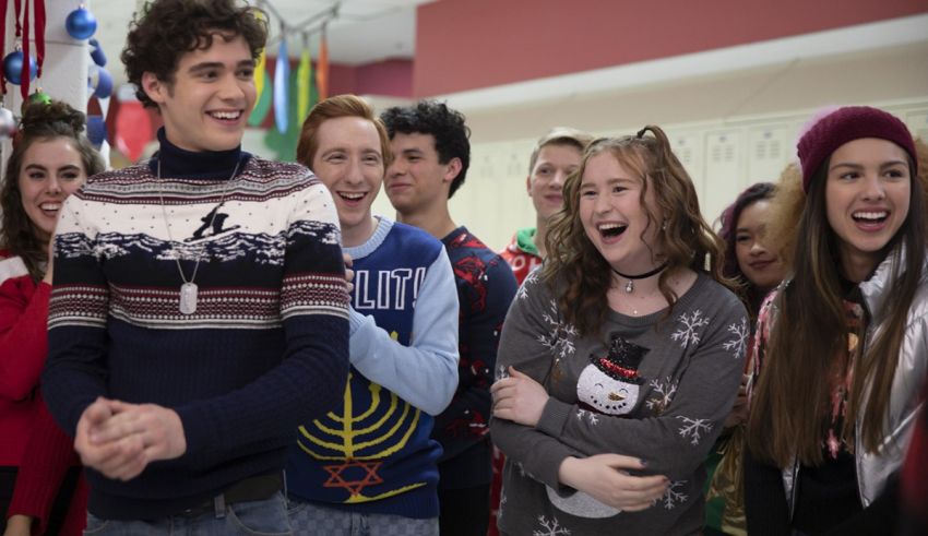 A group of people wearing christmas sweaters in a school hallway.