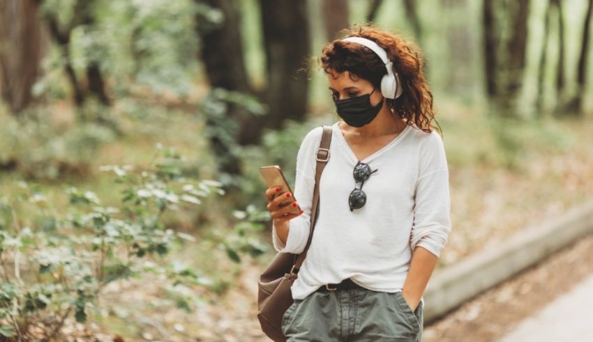 A woman wearing a face mask and holding a phone.