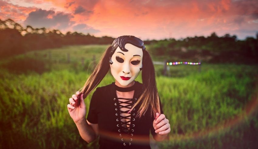 A woman wearing a mask in a field at sunset.