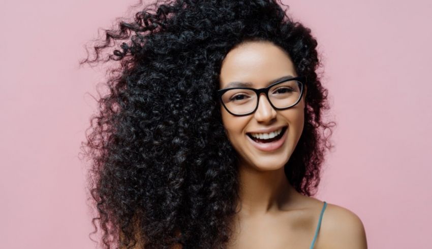 A woman with curly hair and glasses smiling.