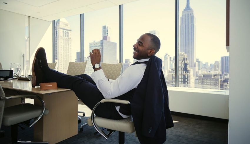 A man in a suit sitting at a desk with a view of the city.