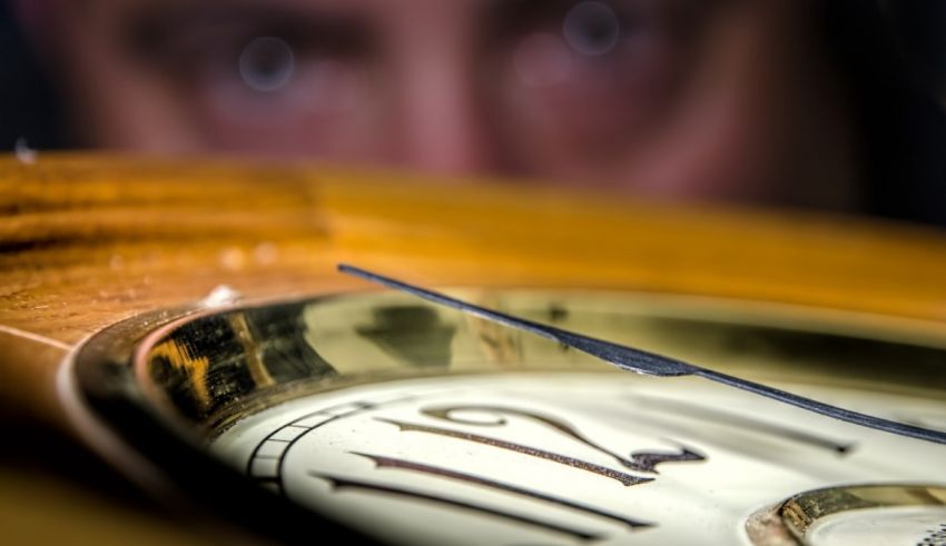 A close up of a man's face looking at a clock.