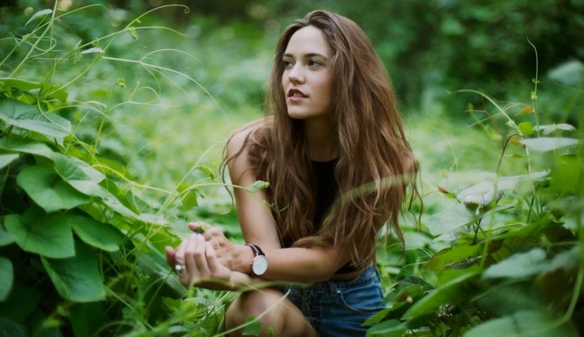 A young woman is sitting in the middle of a green field.
