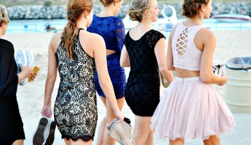 A group of girls in dresses walking down the beach.