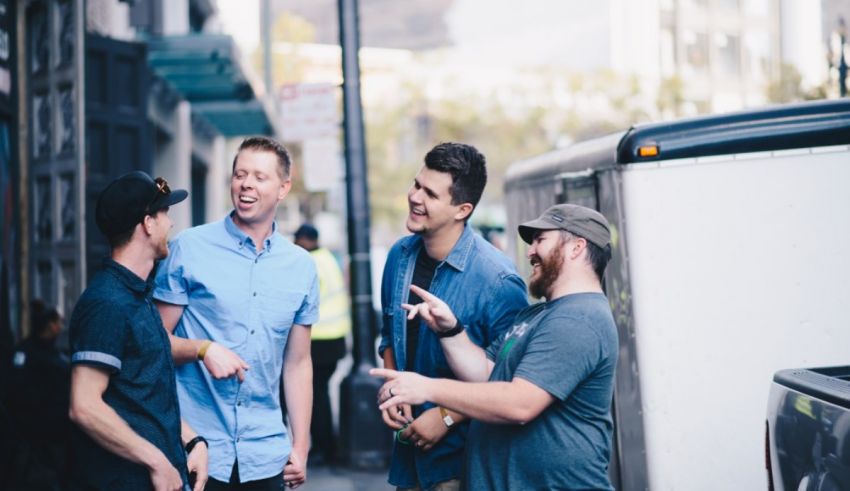 Four men standing on a street talking to each other.