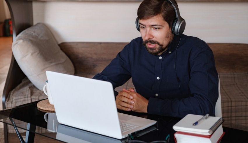 A man wearing headphones and looking at a laptop.