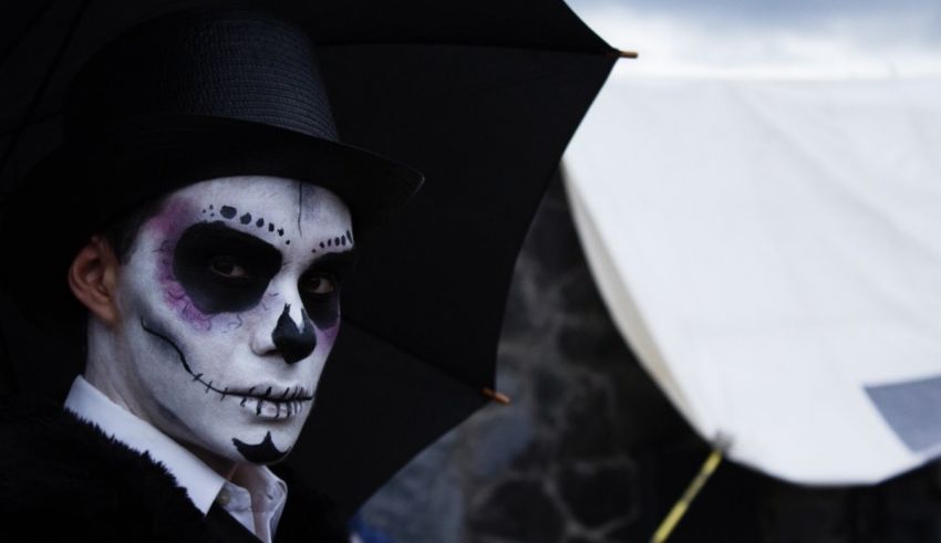 A person with face paint and a hat and umbrella.
