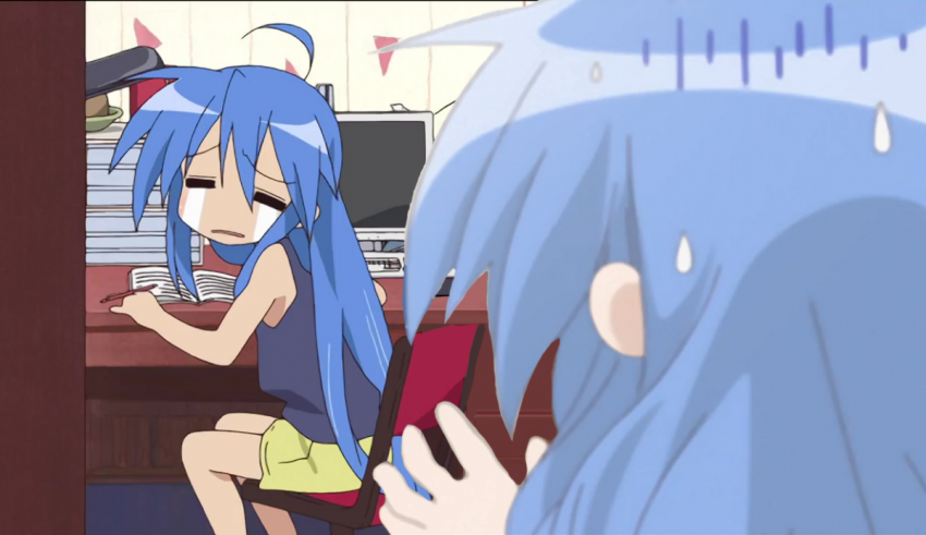 A blue haired girl is sitting in front of a computer.