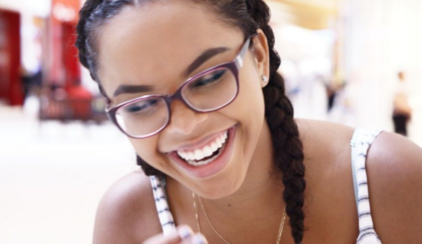 A woman wearing glasses is smiling while holding a cell phone.
