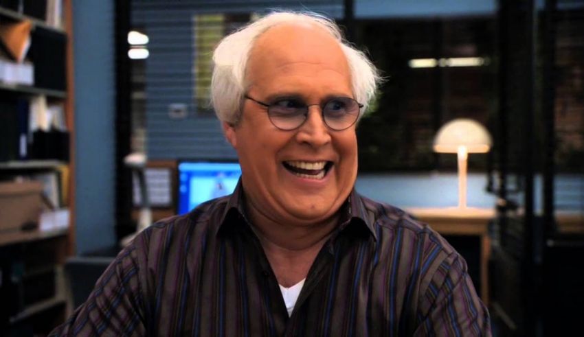 A man with glasses is smiling in an office.