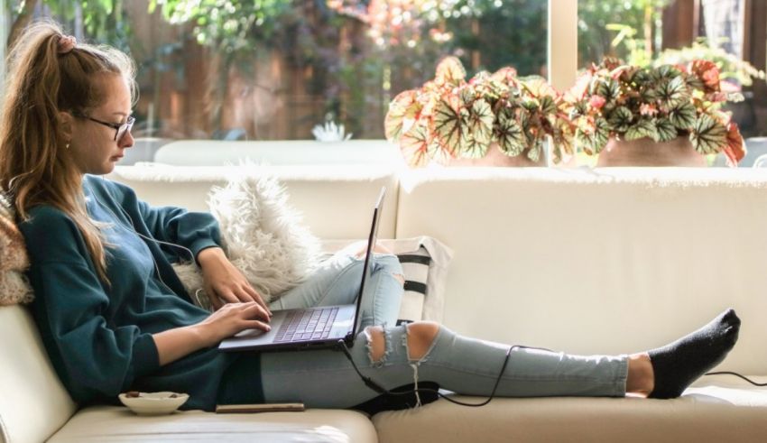 A woman sitting on a couch using a laptop.