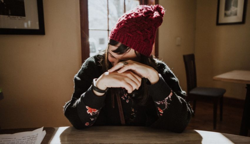 A woman wearing a red beanie sitting at a table.