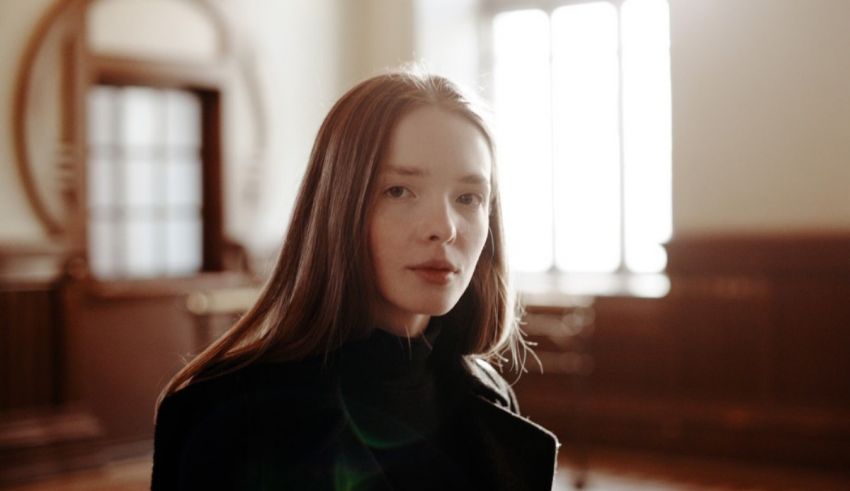 A young woman in a black coat is staring at the camera.