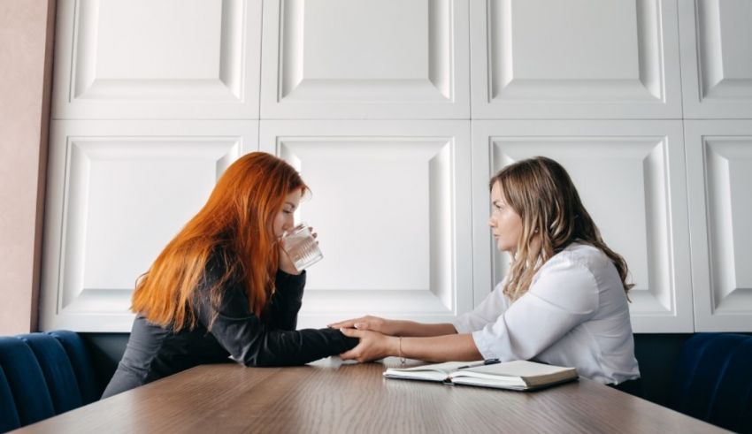 Two women talking at a table in a conference room.