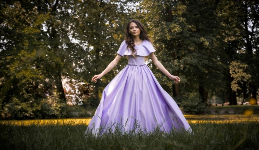 A girl in a purple dress is standing in a field.