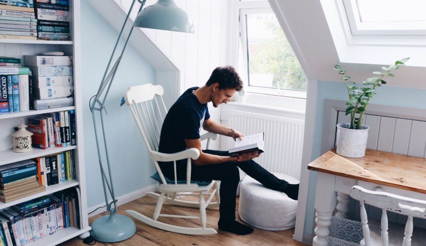 A man sitting in a rocking chair reading a book.