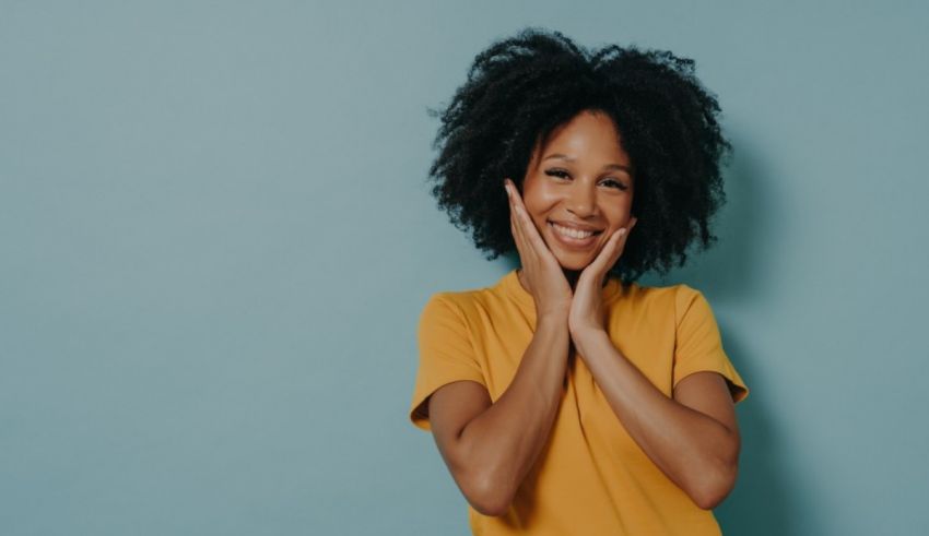 Smiling african american woman with afro hair posing against a blue background.