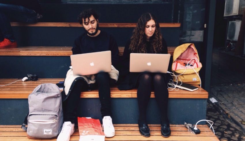 Two people sitting on steps with laptops.