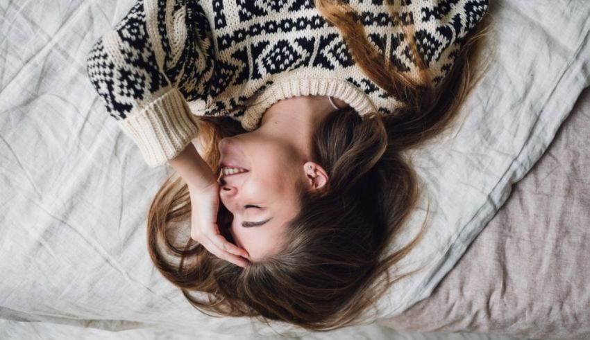 A woman laying on a bed with her head in her hands.