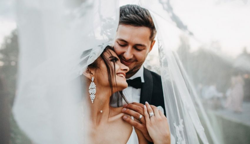 A bride and groom embracing under a veil.