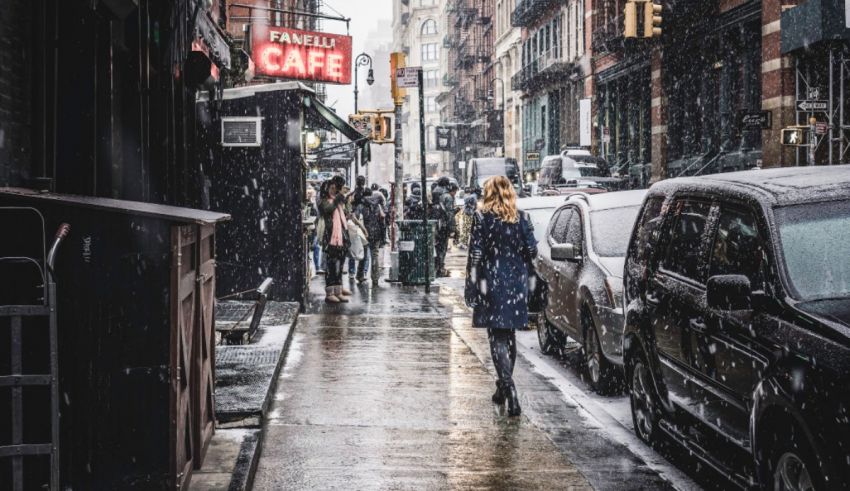 A woman walks down a snowy street in new york city.