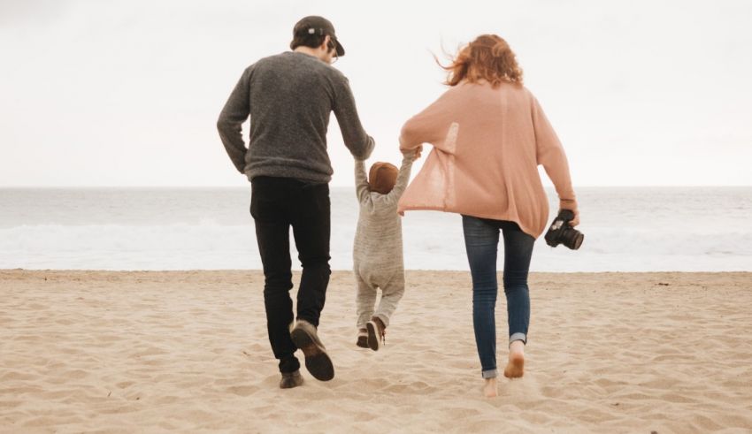 A family is running on the beach with their child.