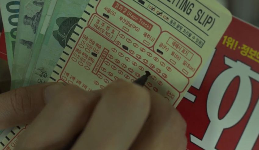 A person holding a lottery ticket in front of a pile of money.