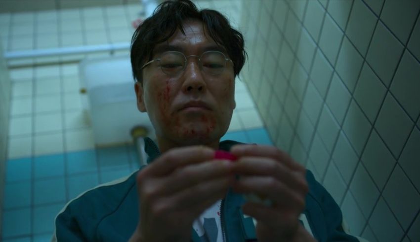 An asian man in a bathroom with blood on his face.